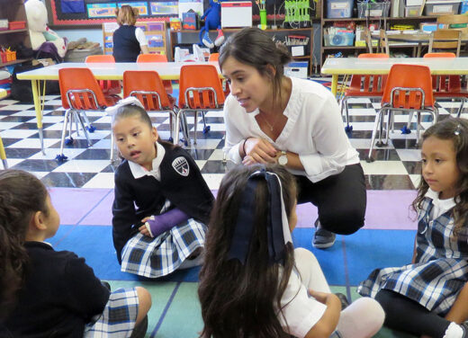 Teacher speaking with young students.